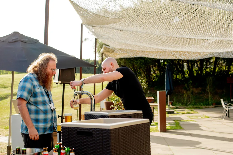 A Close teammate pouring a beer for a colleague at the retreat