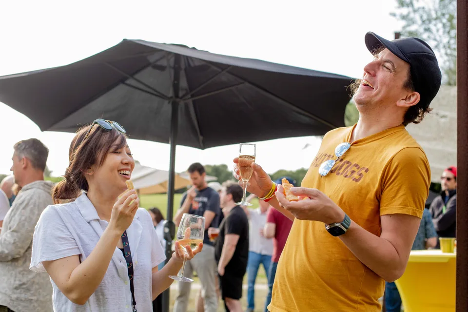 Two Close teammates laughing over drinks under an umbrella
