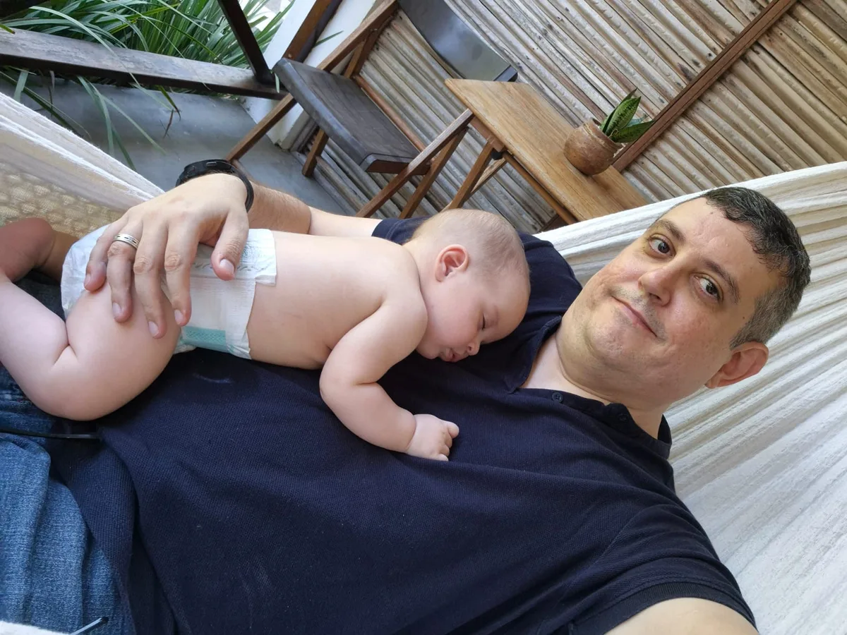A teammate relaxing in a hammock with his baby asleep on his chest